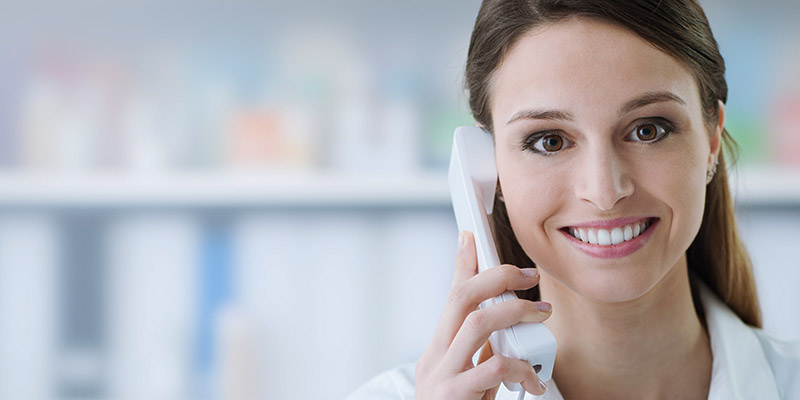 Smiling female doctor holding a receiver and answering phone calls, medical service